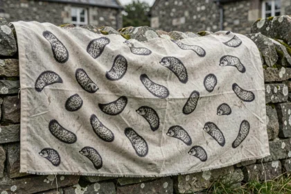 Drapeau breton gwenn-ha-du avec les onze hermines disposées sur tissu ancien accroché à un mur en granit breton